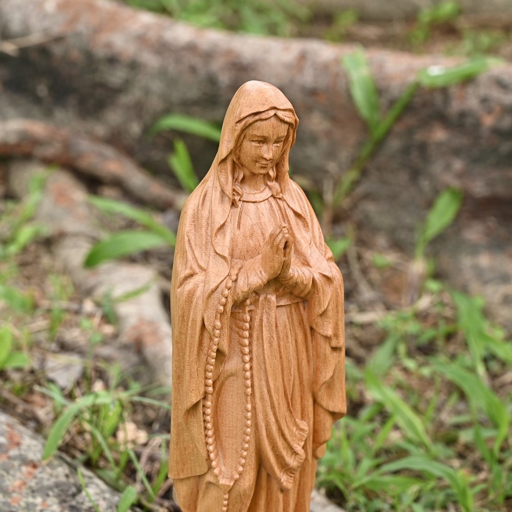 Close up view of Lourdes Virgin Mary wooden statue showing facial details, rosary and handcrafted carving