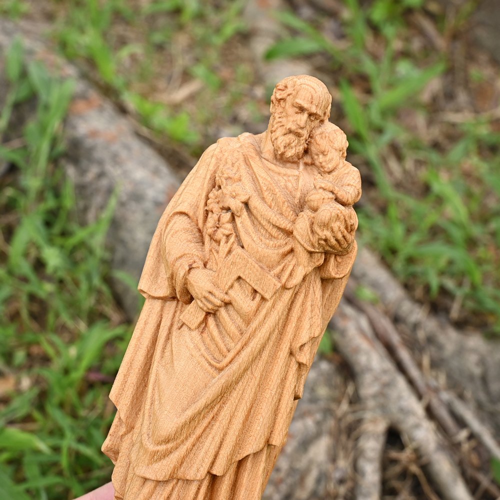 Close view of handmade Saint Joseph wooden sculpture showing carved robe details and craftsmanship