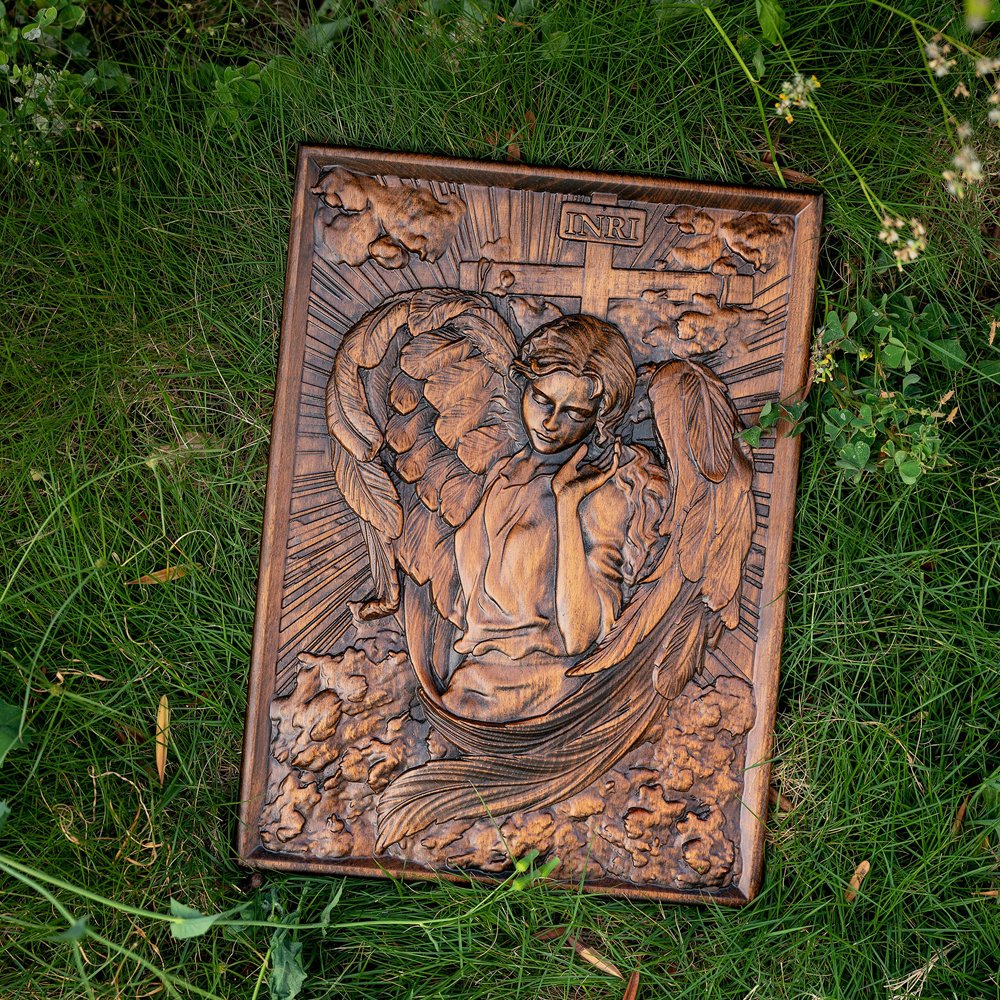 Female Angel wood relief placed on grass, showing handmade wooden angel carving in natural light
