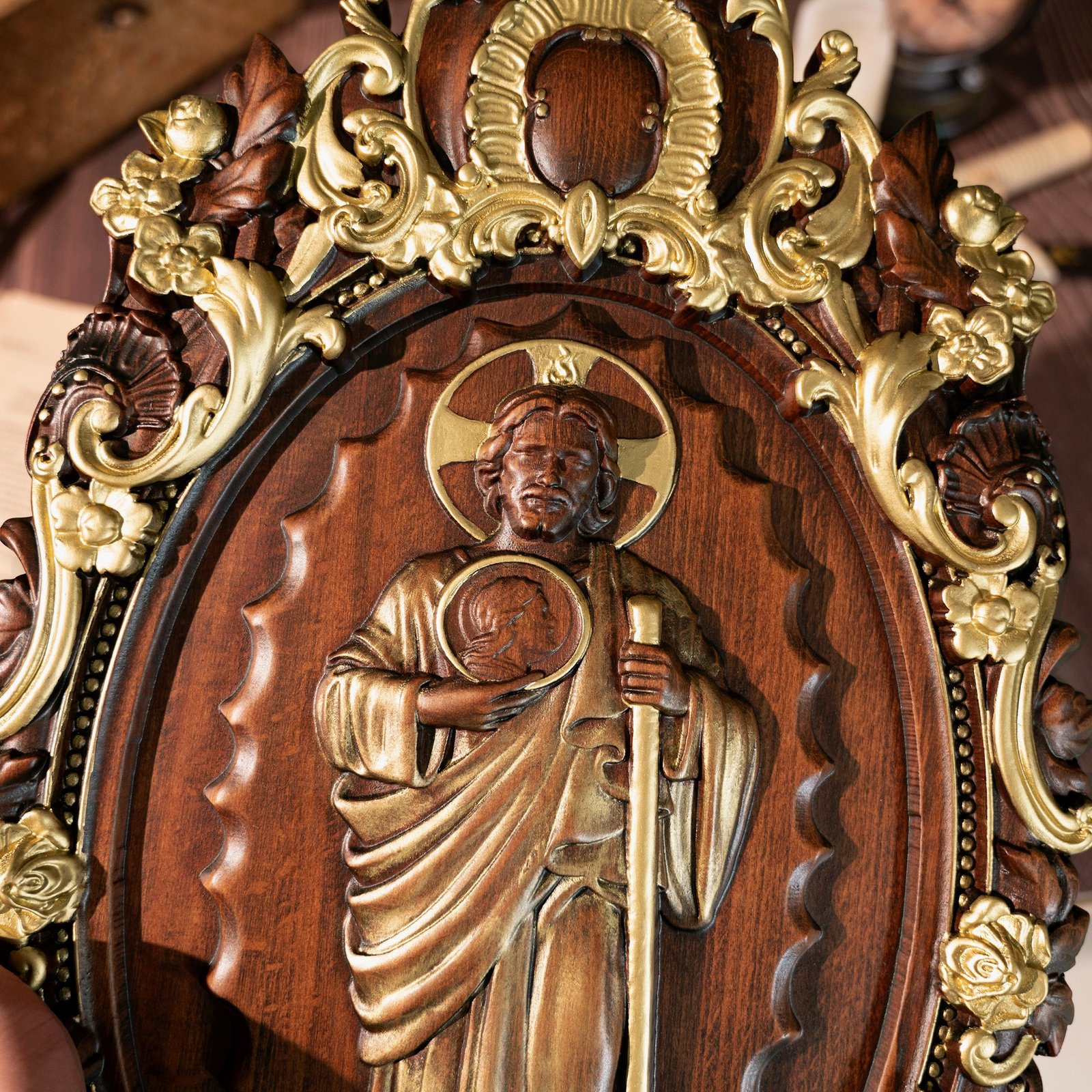 Close up of Saint Jude wooden statue showing carved facial details, robe texture and religious symbolism