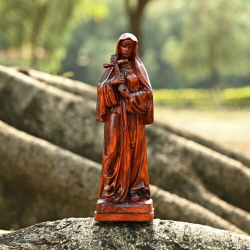 Saint Teresa of Avila wooden statue standing on stone in an outdoor setting with natural light