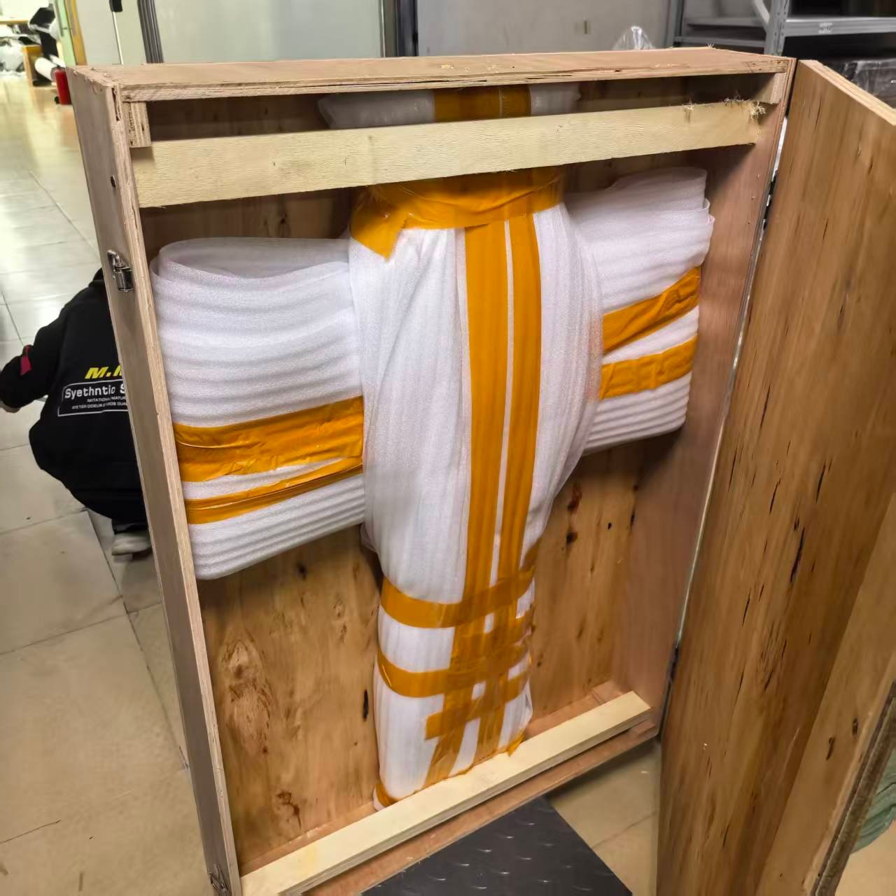 Large wood carving wrapped in layered foam and secured inside a wooden crate