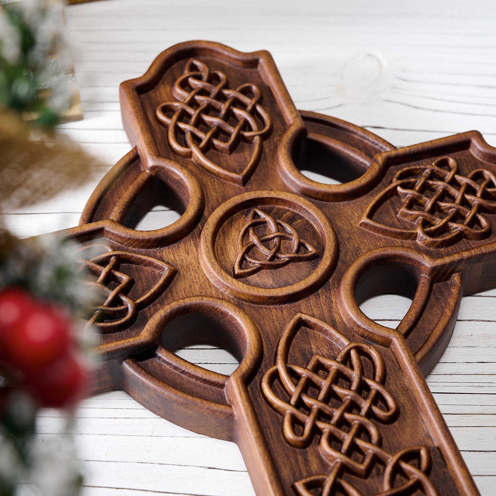 Close-up detail of carved Celtic knotwork and the central Trinity knot symbol on a dark wood cross