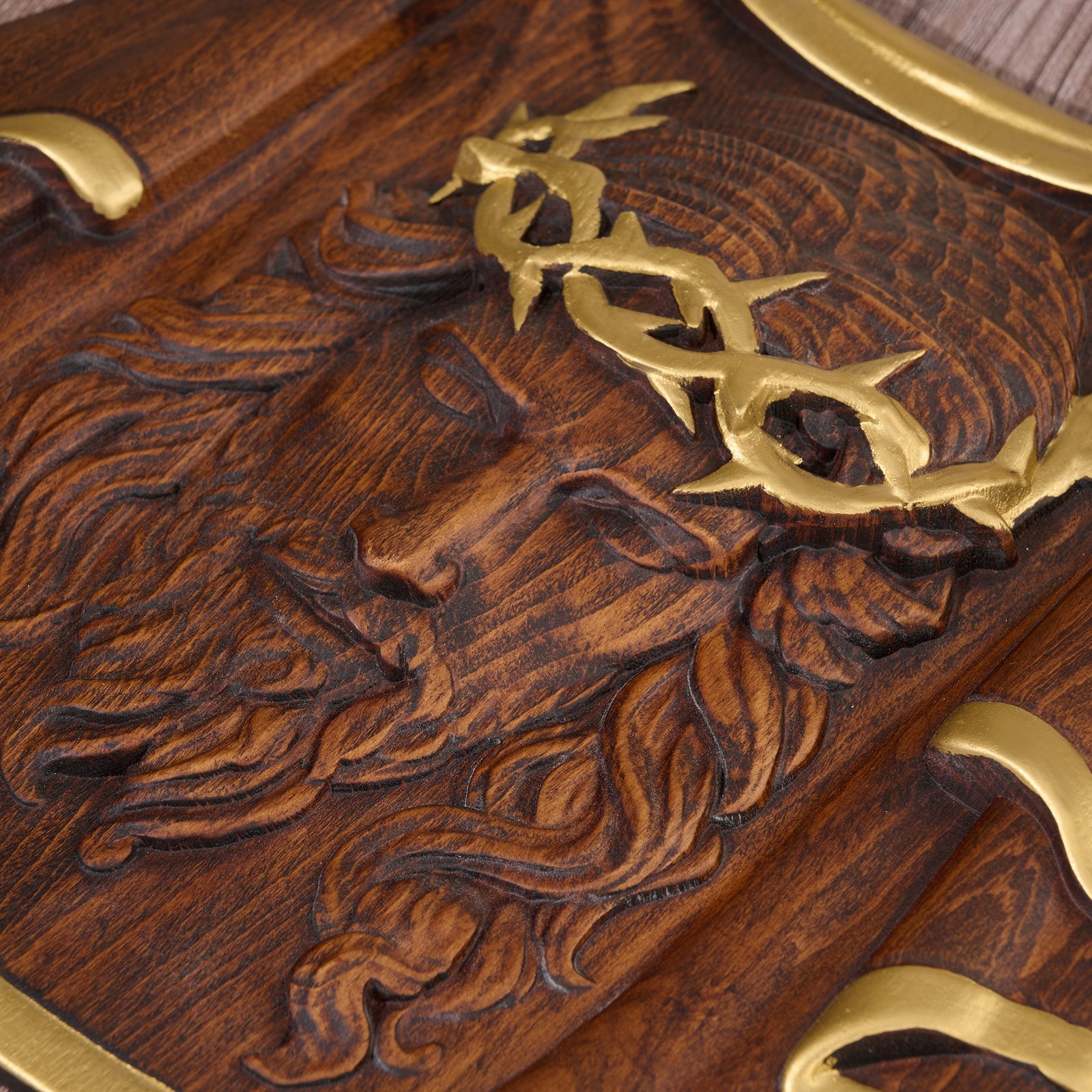 Close-up detail of the gold crown of thorns and carved Jesus face on a wooden religious wall plaque